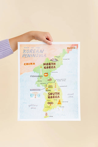 Hand holding a map of the Korean peninsula featuring North and South Korea