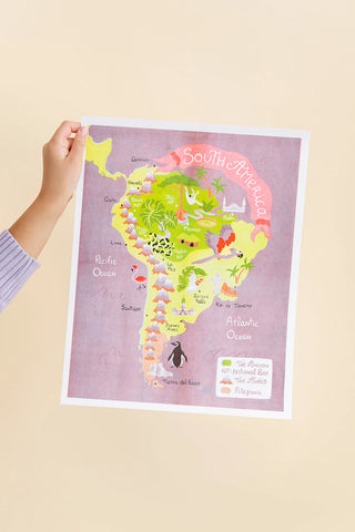 Hand holding a map of South America featuring cities and topography of the continent.